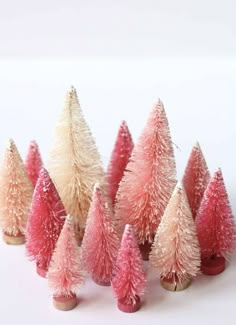 small pink and white christmas trees are lined up in a row on a white surface