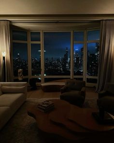 a living room filled with furniture and large windows overlooking the city lights at night time