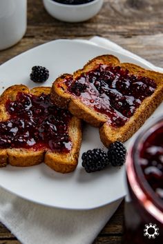 two pieces of toast with jam and blackberries on it sitting on a white plate