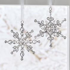 two snowflakes hanging from strings in front of a window