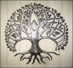 a metal tree wall hanging on the side of a wooden wall with leaves and branches