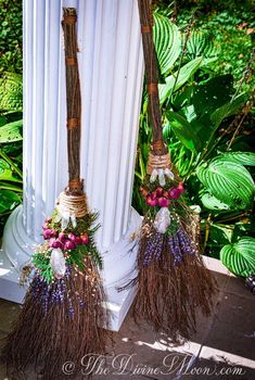 two brooms are decorated with flowers and leaves on the side of a white pole