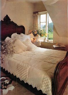 a bed sitting under a window in a bedroom next to a wooden headboard and foot board