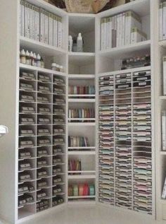 a white bookcase filled with lots of books next to a wall full of binders