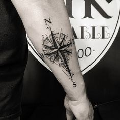 a black and white photo of a man's arm with a compass tattoo on it