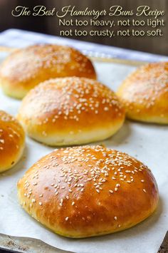 bread rolls with sesame seeds on top sitting on a baking sheet in front of an advertisement for the best hamburger buns recipe