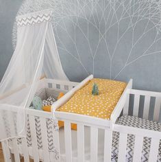 a white crib with a yellow bedding in it