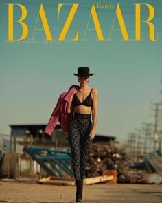 a woman walking down a street in front of a magazine cover with the word bazaar on it