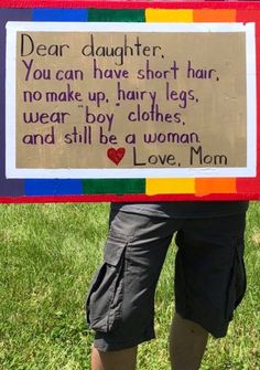 a woman holding up a sign that says dear daughter you can have short hair, no make up, hairy legs, wear boy clothes and still be a woman