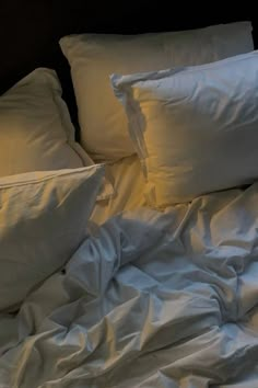 an unmade bed with white sheets and pillows