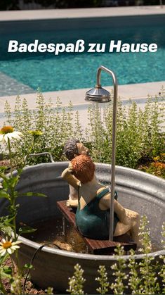 a statue of two people sitting in a bathtub next to a swimming pool and flowers