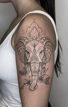 an elephant tattoo on the right arm and shoulder, with flowers around its head in black ink