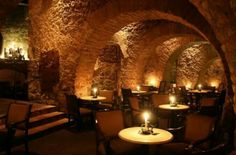 a dimly lit dining room with candles on the tables and in the middle of an old brick tunnel