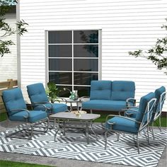 a patio furniture set sitting on top of a rug in front of a white house