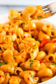 a fork full of macaroni and cheese being lifted from a bowl