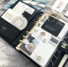 a black and white planner with gold accents on it, surrounded by other personal items