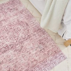 a pink rug on the floor next to a bed