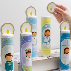 a person is holding some candles in front of several small ones on a book shelf