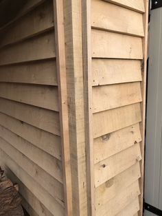 the side of a house with wood siding on it's sides and a door in the back