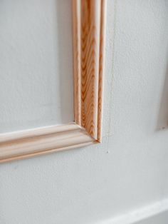 the corner of a white wall with wood trimming on it's edge and an unfinished window frame