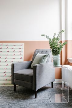 a gray chair sitting in front of a window next to a plant