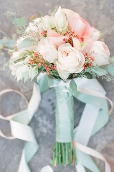 a bridal bouquet with roses and greenery tied to it's side on the ground