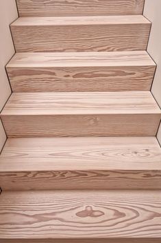 wooden steps leading up to the top of a building with white walls and wood flooring