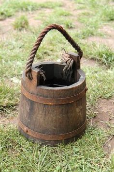 an old wooden bucket with rope on the grass