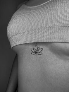 a black and white photo of a woman's stomach with a lotus tattoo on it