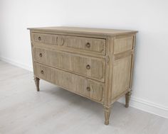 an old wooden dresser sitting on top of a hard wood floor next to a white wall