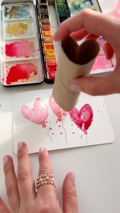 someone is painting hearts with watercolors on the paper and using a glue stick