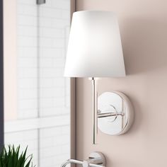 a white lamp on the wall next to a mirror