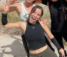 three women posing for a photo with one holding her arm up and the other smiling