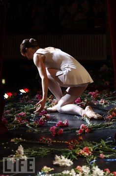 a woman kneeling on the ground surrounded by flowers