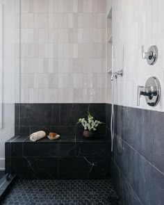 a black and white tiled bathroom with two vases on the shelf next to the shower