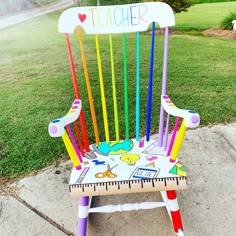 a colorful wooden chair sitting on top of a sidewalk