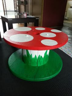 a red and white mushroom table sitting on top of a black rug