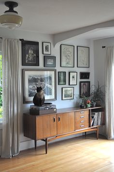 a living room with pictures on the wall and a cat sitting on top of a cabinet