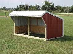 a red and white shed sitting on top of a lush green field