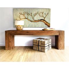 a wooden table sitting on top of a hard wood floor next to a lamp and painting