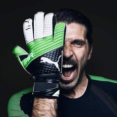 a man with his mouth wide open holding a green and white soccer glove over his face