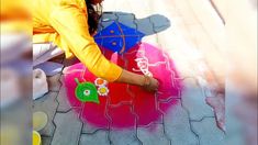 a woman is drawing on the ground with colored chalk