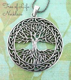 a silver tree of life pendant on a green leafy background with an intricate design