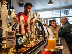 a man standing behind a bar filled with lots of beer