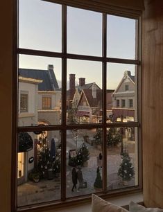 a view out the window of a small town with christmas trees in front of it