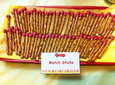 a red tray filled with lots of food on top of a yellow table cloth next to a sign that says match sticks