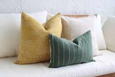 three pillows sitting on top of a white couch