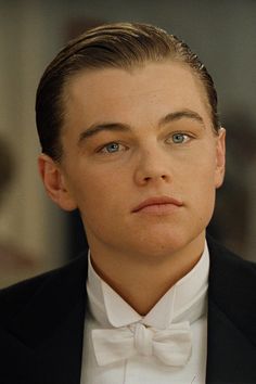 a young man in a tuxedo stares into the distance while wearing a bow tie