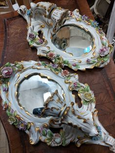 two mirrors sitting on top of a wooden table next to each other with flowers painted on them