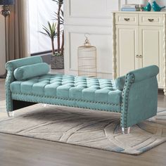 a blue couch sitting on top of a wooden floor next to a white dresser and mirror